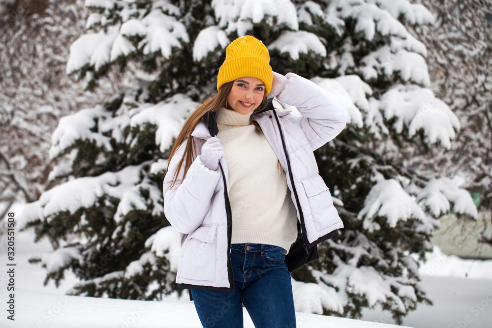 Portrait of a young happy woman on a background of a winter park
