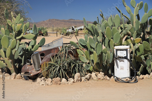 stara opuszczona stacja benzynowa porośnięta kaktusami i wrak samochodu na afrykańskich bezdrożach