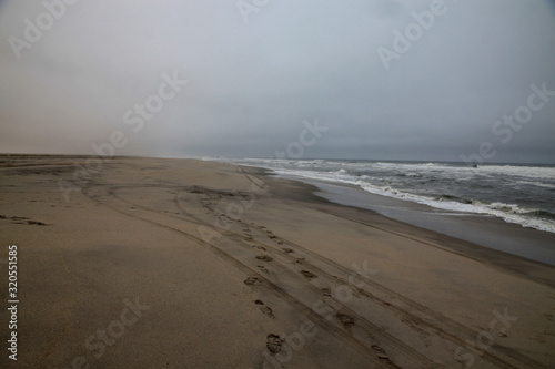 pusta plaża w pochmurny mglisty dzień i ślady na piasku