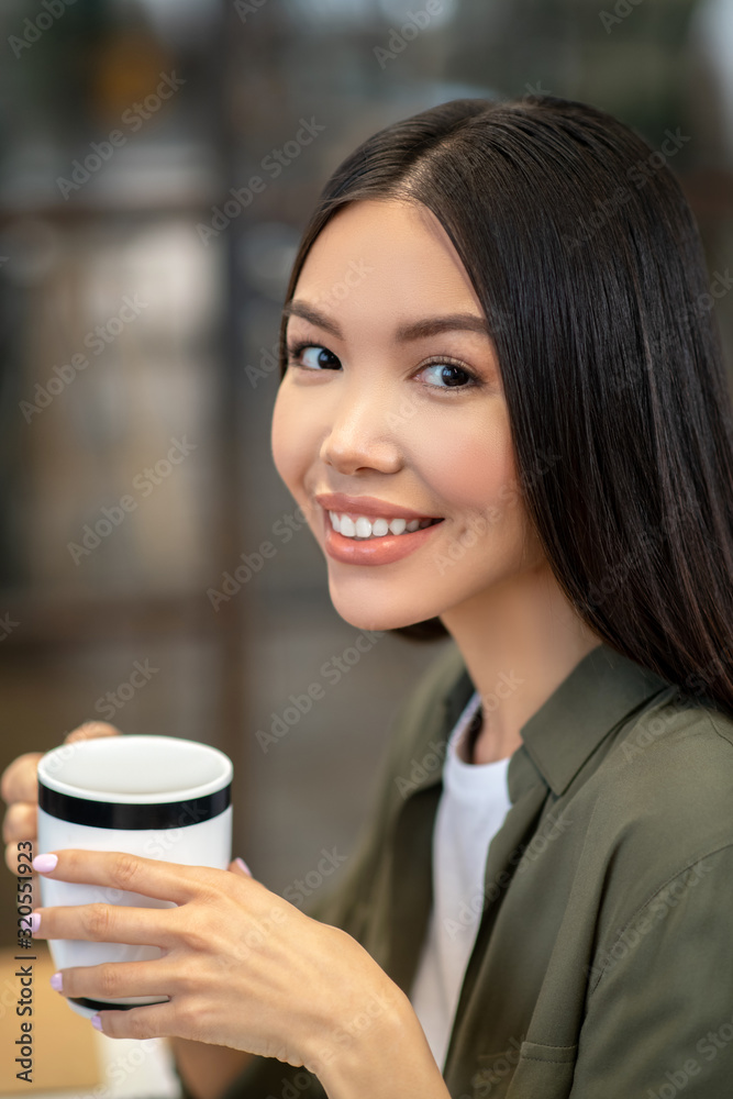 Long-haired brunette asian girl sitting and having coffee Long-haired brunette asian girl sitting and having coffee