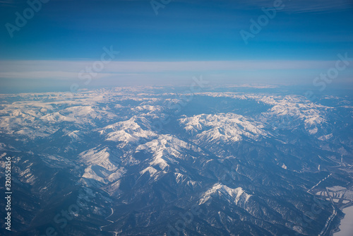 Winter peak mountains with snow from the plane window.
