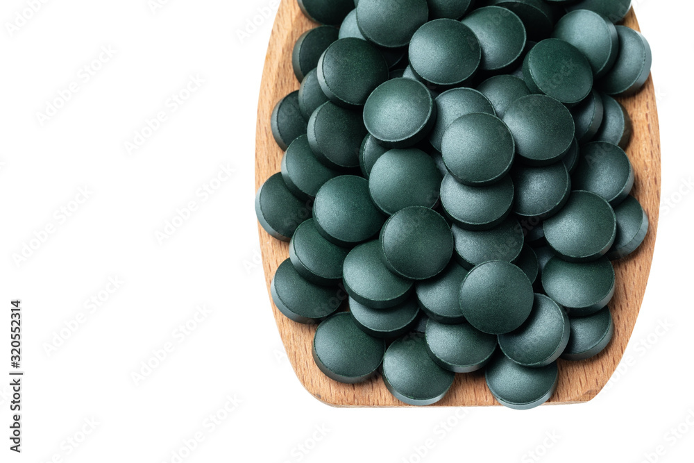 Vitamin and mineral supplements for vegetarians spirulina in tablets in a wooden spoon, close-up. Vitamin and mineral supplements for vegetarians spirulina in tablets in a wooden spoon, close-up.