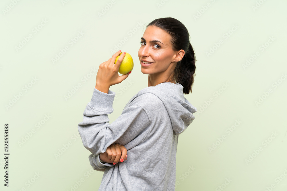 Young sport woman with an apple over isolated green background Young sport woman with an apple over isolated green background