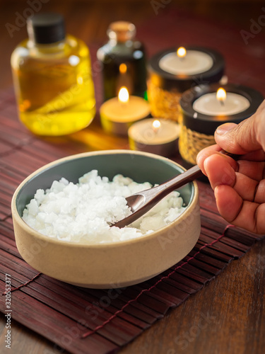 Scoop up the pure mineral sea salts with bottles of massage oil and aromatheray candles in the background (Thai style)