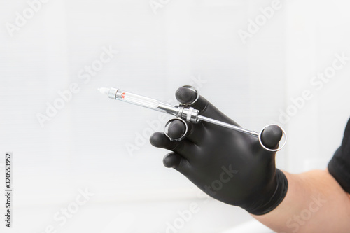 Dentist's hand in a black glove holding a dental syringe. for local anesthesia