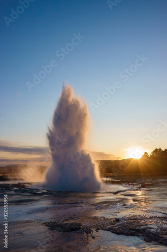The Geysir water mist after eruption with blue skye during sunset in Iceland.