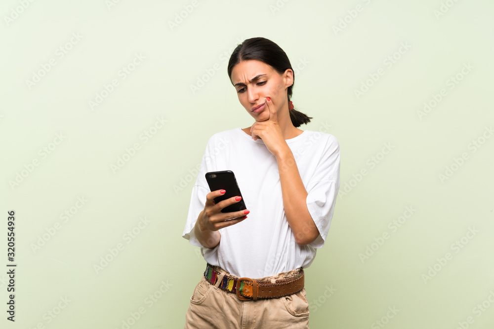 Young woman over isolated green background using mobile phone Young woman over isolated green background using mobile phone