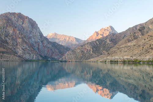 Mirror surface of Lake Iskanderkul at dawn amid the mountains