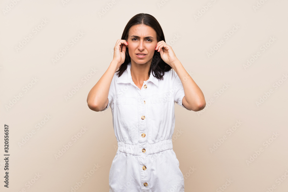 Young woman over isolated background frustrated and covering ears