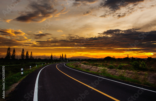 open road with beautiful sunset and golden sky. Highland road.
