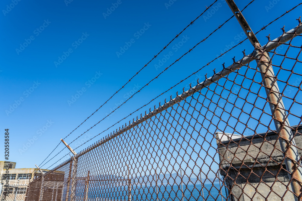 Metal fence with barbed wire on a restricted area Metal fence with barbed wire on a restricted area
