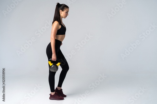 Fitness woman exercising crossfit holding kettle bell. Fitness instructor on white background