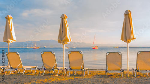 Empty deck chairs and closed umbrellas on a sandy beach. Travel background. Start of the season on the beach. Beautiful landscape and seascape. Postcard, greeting card, brochure. view from backside