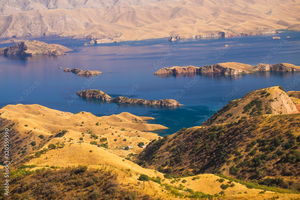 Beautiful blue waters of Nurek reservoir and golden shores