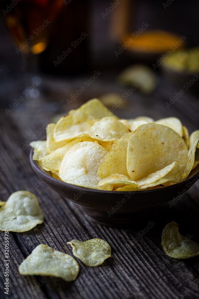 Crunchy delicious potato chips for a tasty snack break on dark rustic background