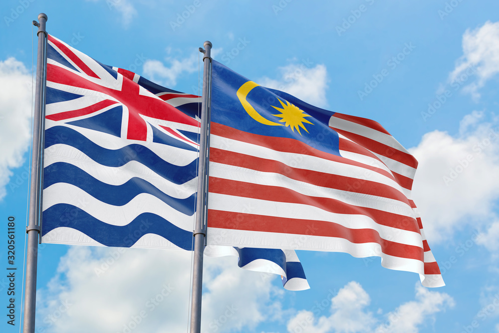 Malaysia and British Indian Ocean Territory flags waving in the wind against white cloudy blue sky together. Diplomacy concept, international relations.