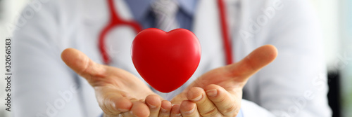 Fotografering Male medicine doctor hands holding and covering red toy heart