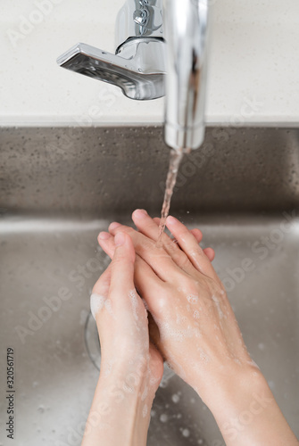 Asian woman washing hands in a sink