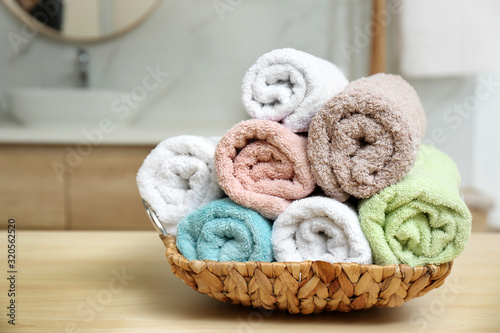 Rolled fresh towels on wooden table in bathroom, closeup