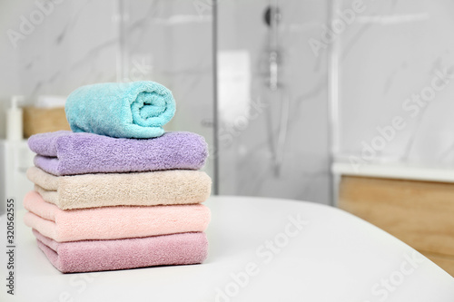 Stack of fresh towels on white table in bathroom. Space for text