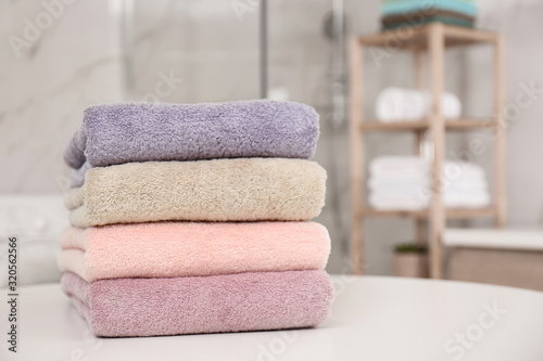 Stack of fresh towels on white table in bathroom, closeup