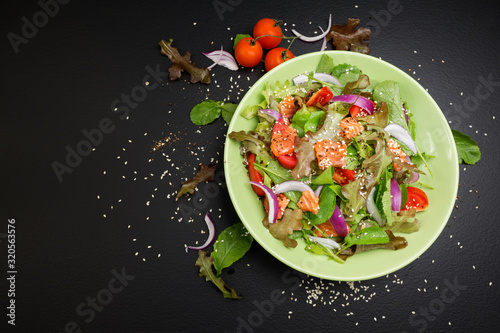 Fresh salmon salad with tomatoes Fresh green onions and vegetables On a black background
