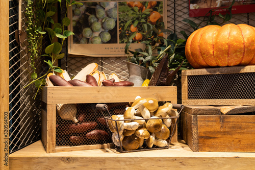 Pumpkin, mushrooms, eggplant, potatoes displayed on a wooden box. Vegetables and fake plants decoration.