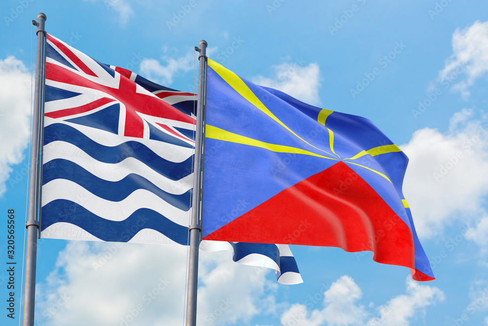 Reunion and British Indian Ocean Territory flags waving in the wind against white cloudy blue sky together. Diplomacy concept, international relations.