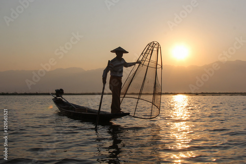 Myanmar fisherman of the Inle Lake at the dawn fishes well-known method with the  bamboo basket © nelasova