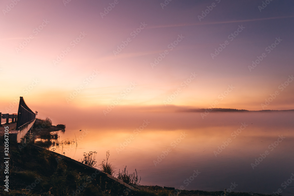 Early morning on the lake with a pink dawn and shrouded haze of mist, a mesmerizing mysticism of nature