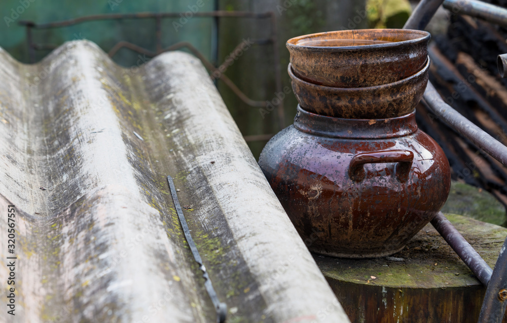 Remains of blackened pottery that survived the fire, against the background of burned boards and metal structures. Careless handling of fire. Remains of blackened pottery that survived the fire, against the background of burned boards and metal structures. Careless handling of fire.