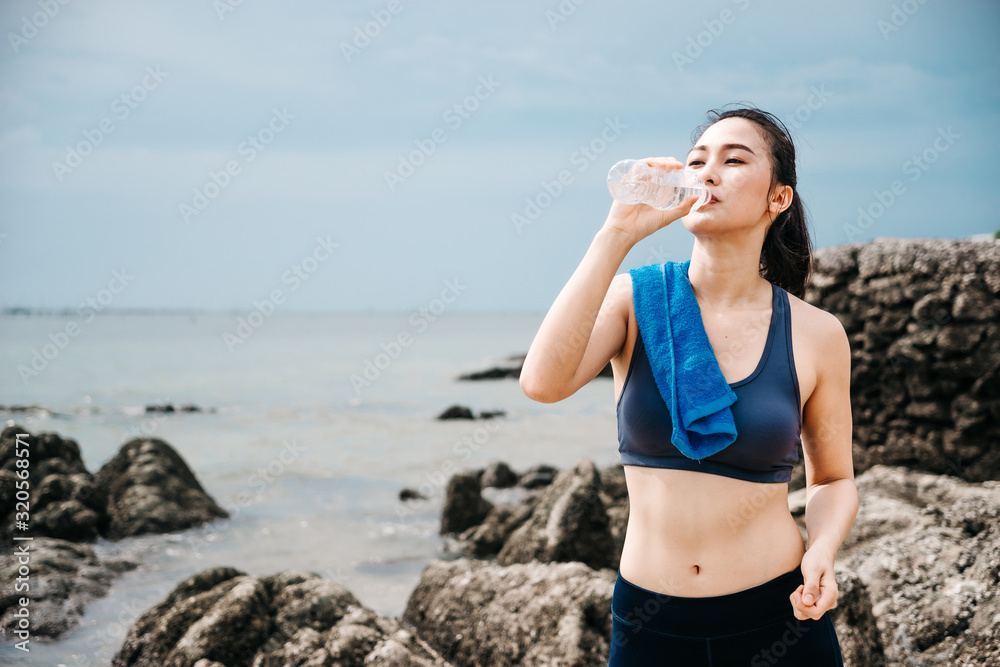 Young Asian woman athlete drinking water after exercising to revitalize Young Asian woman athlete drinking water after exercising to revitalize