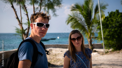 man with a backpack and a woman standing on the beach with sunglasses in Tanzania, Africa © LP Productions
