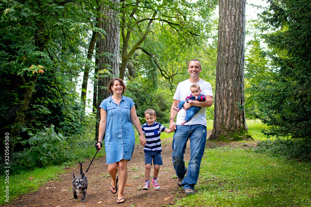 Young happy family walking through the park with their dog