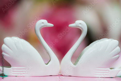 Fototapeta Naklejka Na Ścianę i Meble -  Two small plastic swans laid face to face, forming a heart shape.