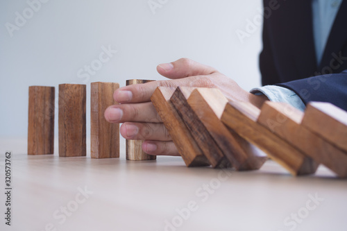 Protection finance from domino effect concept. Hands stop domino effect before destroy stack of money.