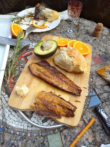 Clupea harengus, Atlantic herring slice of avocado, slice of orange and traditional bread in white plate