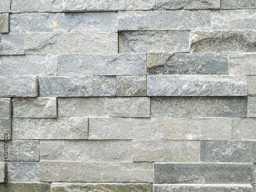 Modern stone rock tile bricks for wall in light grey color with surface left uneven on purpose for decorative effect, made of natural material