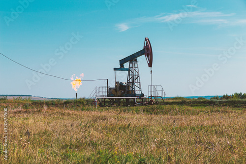 Oil pumpjack and gas torch on oil production
