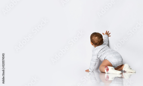 Quadro em tela Baby girl in gray bodysuit and socks with red bows