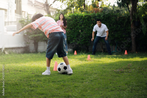 A boy is playing football, with his parents playing, family relationships.