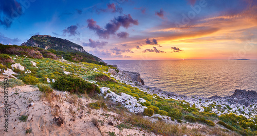 Amazing sunset view with multicolored clouds. Incredibly romantic sunrise on Voidokilia beach, Ionian Sea, Pilos town location, Greece, Europe. View of the ocean through the rocky shore. © zicksvift