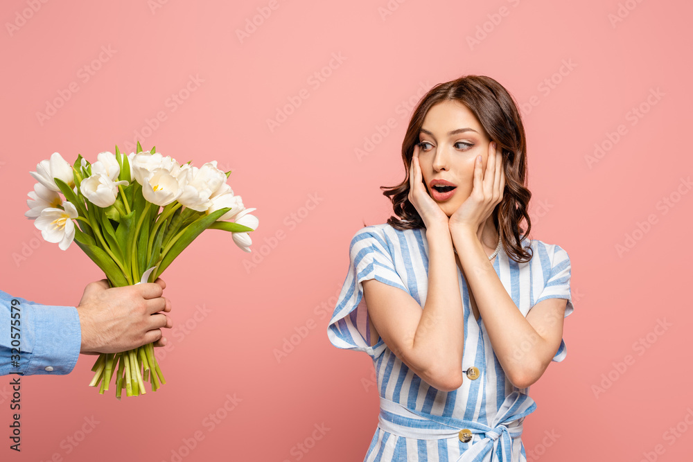 cropped view of man presenting bouquet of white tulips to surprised young woman isolated on pink cropped view of man presenting bouquet of white tulips to surprised young woman isolated on pink