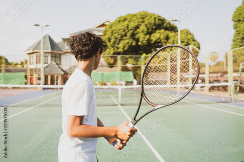 young boy holing tennis racket and playing sport