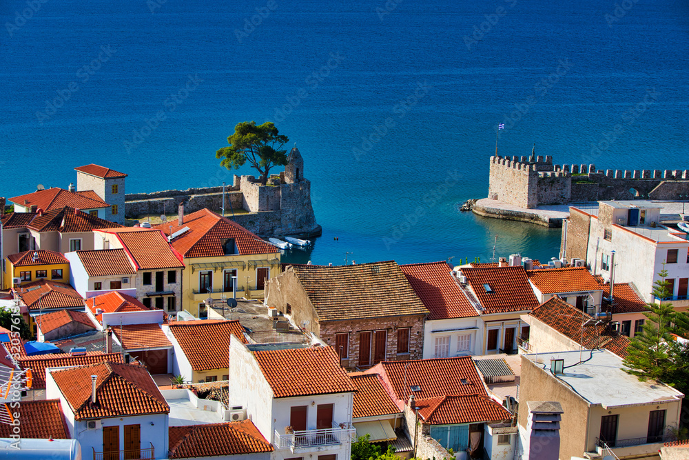 Old Greek port Nafpaktos with ancient castle walls an background and fishing boats at foreground. Epic lilac colored sunrise sky over sea scenery. Famous travel destination in Greece. Gulf of Corinth