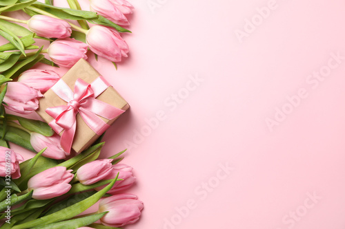 Beautiful tulips and gift box on pink background, top view