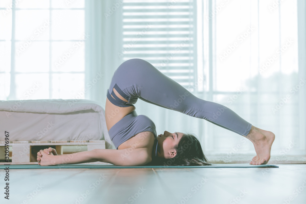 Attractive Asian woman practice yoga Halasana pose or plow pose to meditation in bedroom after wake up in the morning with warm light Feeling so comfortable and relax,Healthcare Concept Attractive Asian woman practice yoga Halasana pose or plow pose to meditation in bedroom after wake up in the morning with warm light Feeling so comfortable and relax,Healthcare Concept