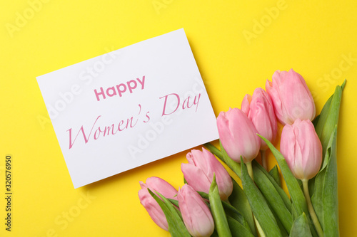 Fototapeta Naklejka Na Ścianę i Meble -  Pink tulips and inscription Happy women's day on yellow background, top view