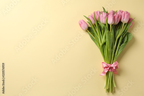 Bouquet of pink tulips on beige background, space for text © Atlas