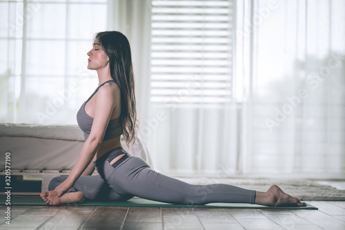Attractive Asian woman practice yoga pigeon pose to meditation in bedroom after wake up in the morning Feeling so comfortable and relax,Yoga for Healthcare Concept